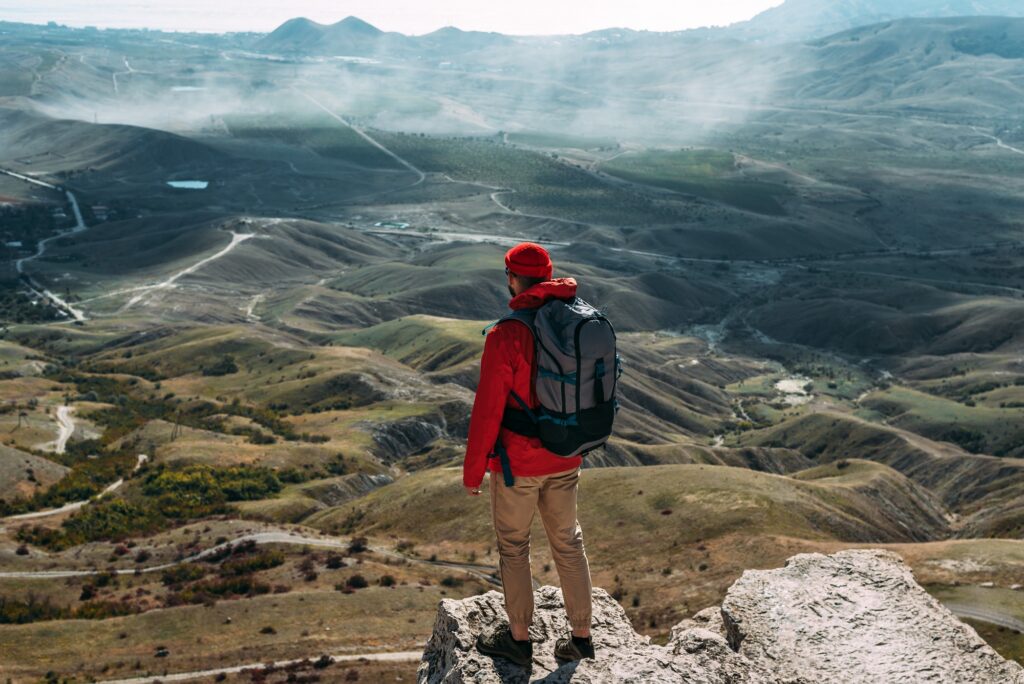 A traveler on the background of mountains. A tourist stands on top of a mountain